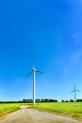 Fototapeta premium Wind generator in the meadows, on a background of blue sky.