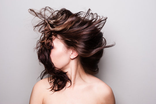 Stop action photograph of a beautiful woman with brunette hair creating motion with her hair.
