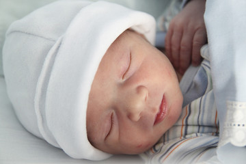 newborn with hours sleeping in the hospital with a hat