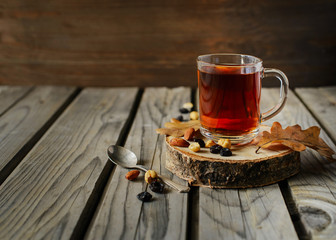 Cuo of tea with nuts and leaves on wood background.
