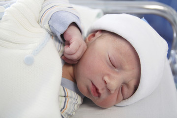 newborn with hours sleeping in the hospital with a hat