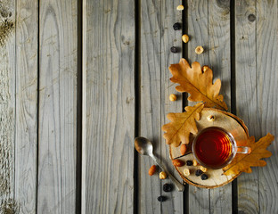 Cuo of tea with nuts and leaves on wood background.