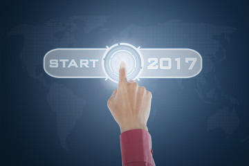 Hand touching start button with 2017