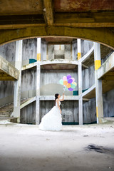 Happy asian woman wearing a wedding dress and holding balloon posing in abandoned building