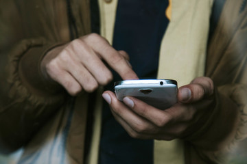 hands with mobile phone behind the glass of the window