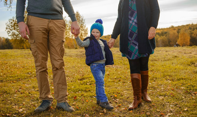 Family of three walking outdoors in the fall.