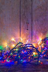 Fototapeta na wymiar Christmas multicolored lights on wooden planked background with copy space