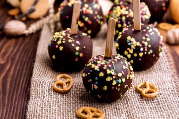 Apples in chocolate glaze on woodentable.