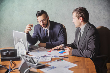 young manager listening to his colleague explanations, discussion of data, two partners negotiating