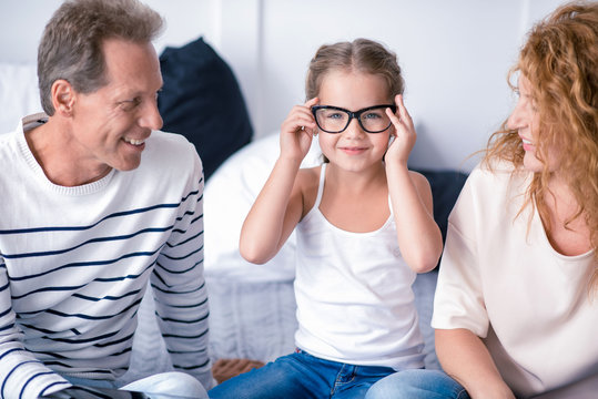 Little girl wearing glasses and smiling with her grandparents