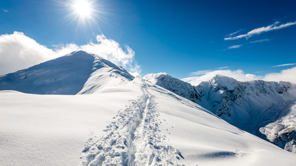 mountain tops in winter covered in snow with bright sun and blue