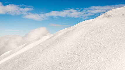 mountain tops in winter covered in snow with bright sun and blue