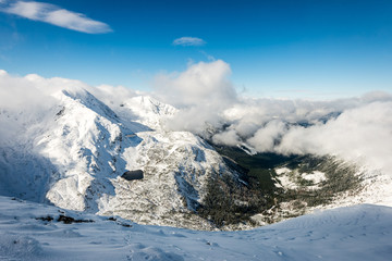 mountain tops in winter covered in snow with bright sun and blue