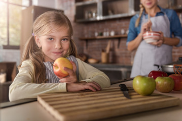 Fototapeta premium Smiling little girl holding apples in the kitchen
