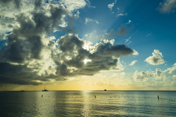sunset on a tropical beach in the caribbean with cloudy skies and calm waters