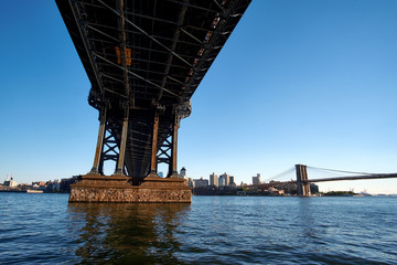 Obraz premium Zbliżenie pod mostem Manhattan w pobliżu jednej z wież pomocniczych, z mostem Brooklyn w oddali