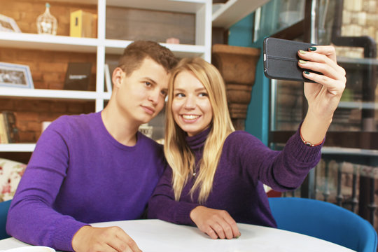 Young couple man and woman doing selfie. Home or a coffee shop