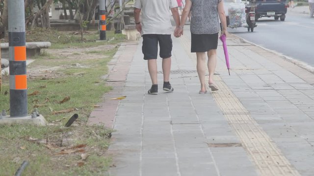 Senior couple taking an unhurried walk along the park lane