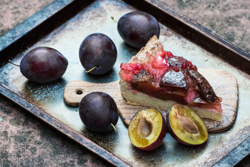 plum pie or tart and plums on rustic background