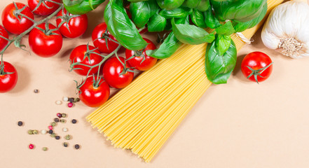 Raw pasta and ingredients for pasta with tomatoes and basil.