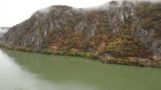 Autumn at the Danube Gorges, the border between Romania and Serbia. View from Serbian part. In the background, on the Romanian bank, the Decebal king's image carved in stone and monastery Mraconia. 4K
