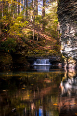 Serene waterfall reflects in the calm water and gorge at Raymondskill Falls near Milford, PA, in fall, portrait
