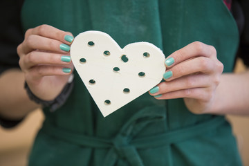Female person hold wooden heart with holes
