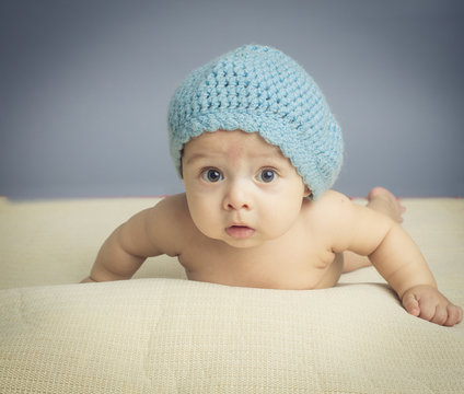 Small baby with sparkle eyes playing on carpet inside studio