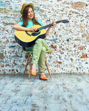 Girl play on acoustic guitar. Grunge wall.