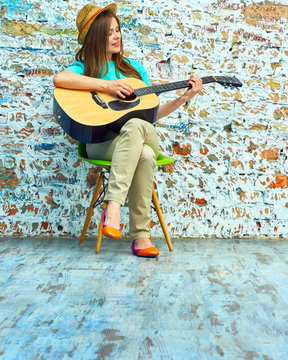 Girl play on acoustic guitar. Grunge wall.