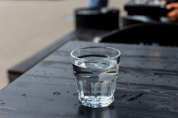A glass of water on the wooden table of a cafe terrace