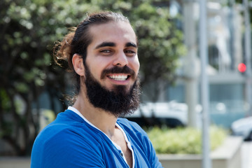 Laughing hipster man with beard and blue shirt in the city