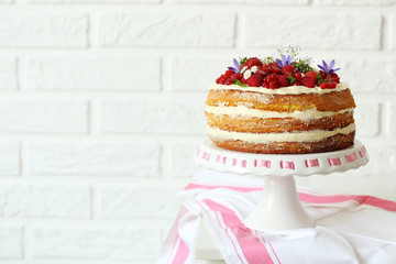 Delicious biscuit cake with berries on brick wall background