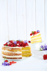 Delicious biscuit cake with berries on white wooden table