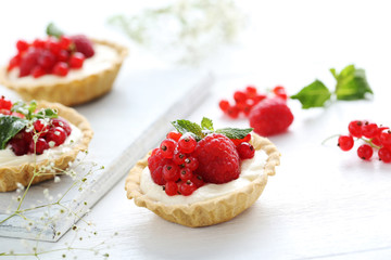 Dessert tartlets with berries on white wooden background