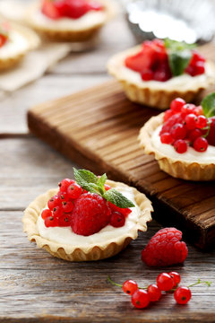 Dessert tartlets with berries on grey wooden background