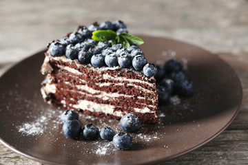 Tasty piece of cake with blueberries on wooden table