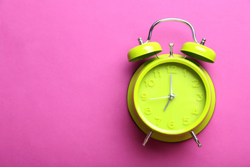 Green alarm clock on a pink background