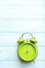 Green alarm clock on a blue wooden table