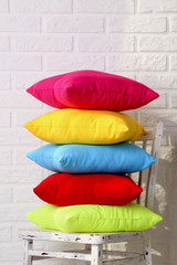 Colorful pillows on chair on white brick wall background