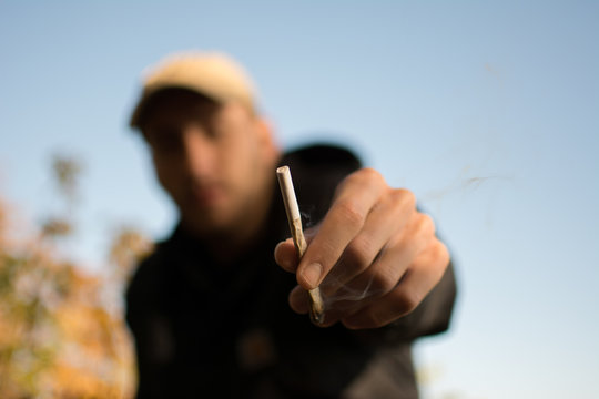 Ein Mann h&auml;lt einen Joint in der Hand