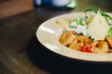 Fresh caesar salad in a circular plate on a wooden table on a blurred background
