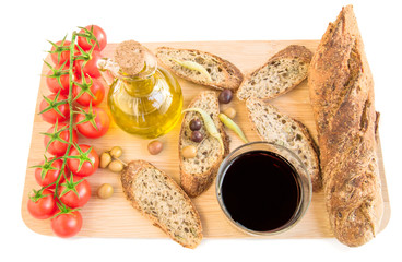 Tray with bread, olives, olive oil, vine, tomatoes on white.
