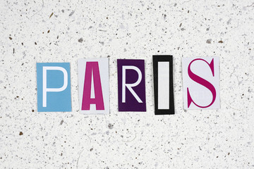 Paris word cut from newspaper on handmade paper texture