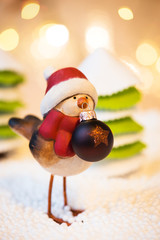 Robin with Christmas ball in a forest, Christmas lights in a background