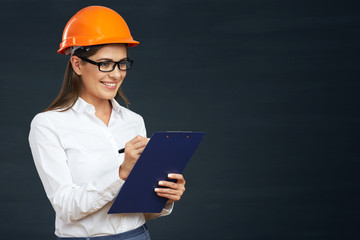 Woman architect writes on clipboard.