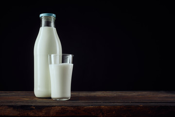 Full bottle of milk beside cup with copy space