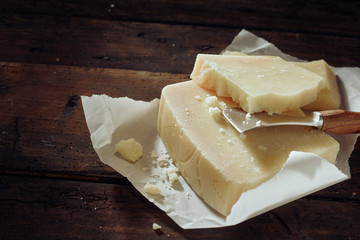 Knife slicing through block of white cheese