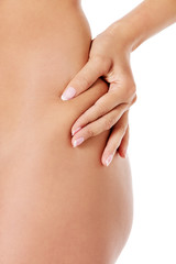 The woman squeezes a skin on a hip for check on a cellulitis.