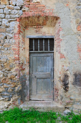 Old wooden door in brick doorway in Tuscan village.